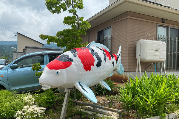 Large inflatable fish sculpture in front of a building with greenery